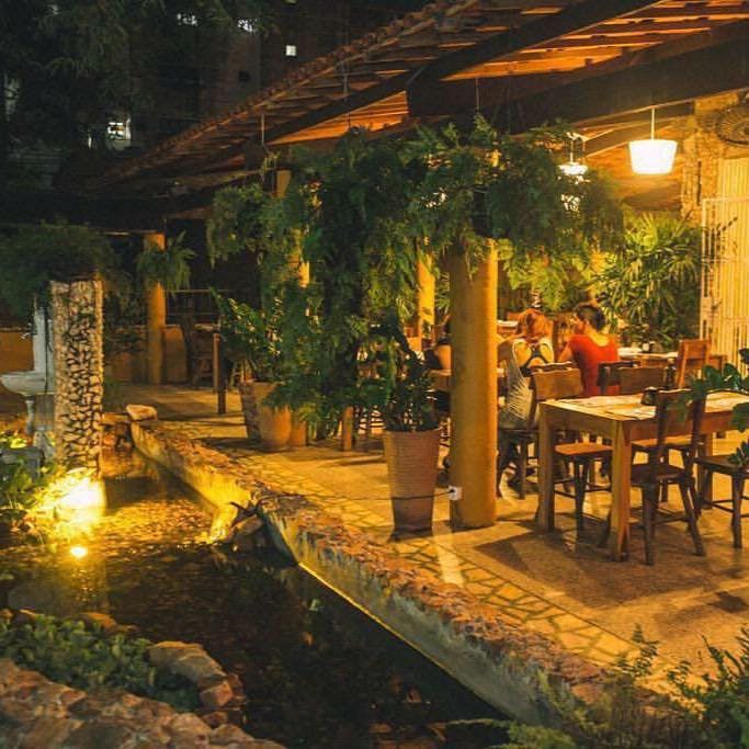 Restaurante rústico com mesas ao ar livre serve opções orgânicas e integrais de massas, pizzas e saladas.